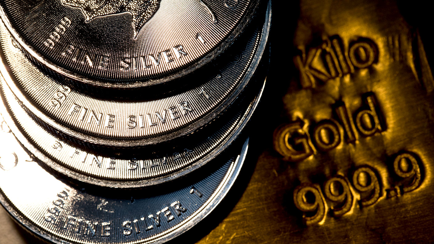 Close-up of fine silver coins and a kilo gold bar